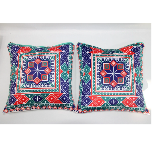 Two square decorative throw pillows with colorful geometric and tribal-inspired patterns in navy blue, red, green, and white, displayed side-by-side against a plain white background.
