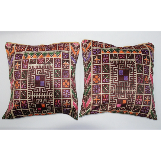 Two square decorative throw pillows with intricate geometric and tribal-style embroidered patterns in brown, purple, orange, green, and beige, displayed side-by-side against a plain white background.
