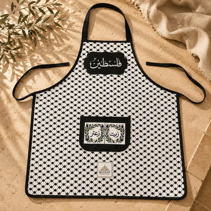 Black and white patterned apron with branding on a beige surface