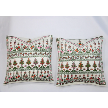 Two square throw pillows with intricate traditional embroidery in green, red, and pink on an off-white background, displayed side-by-side against a plain white backdrop.