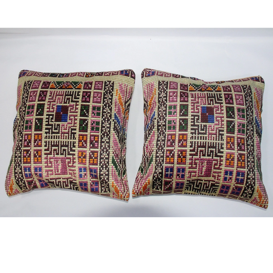 Two square decorative throw pillows with intricate multicolor geometric and tribal-style embroidery, displayed side-by-side against a plain white background.