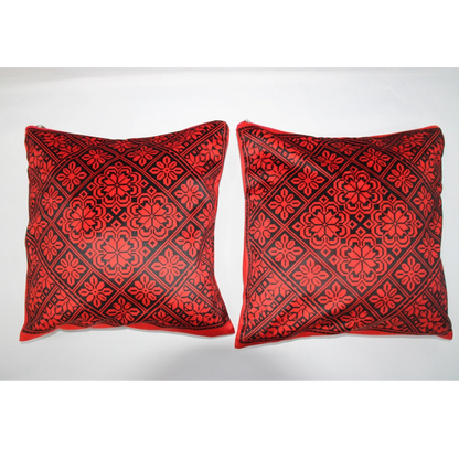 Two square decorative throw pillows with a red and black geometric floral pattern, displayed side-by-side against a plain white background.