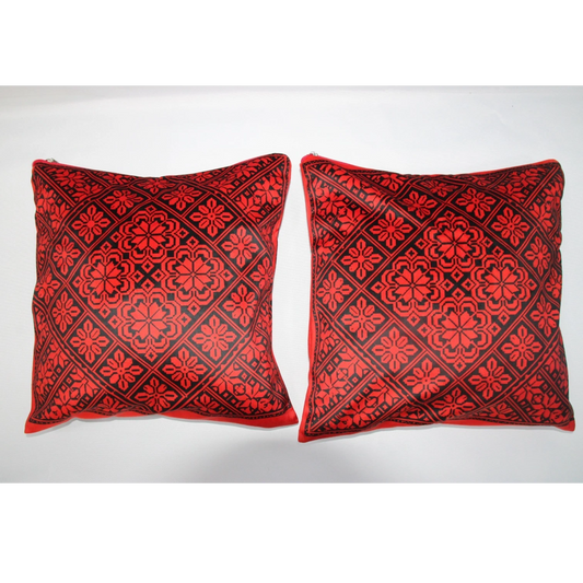 Two square decorative throw pillows with a red and black geometric floral pattern, displayed side-by-side against a plain white background.