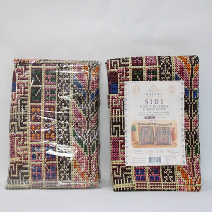 Two folded woven cushion covers with a colorful geometric pattern, shown side by side against a plain light background. The left cushion cover is sealed in clear plastic, and the right one has a white paper label attached.