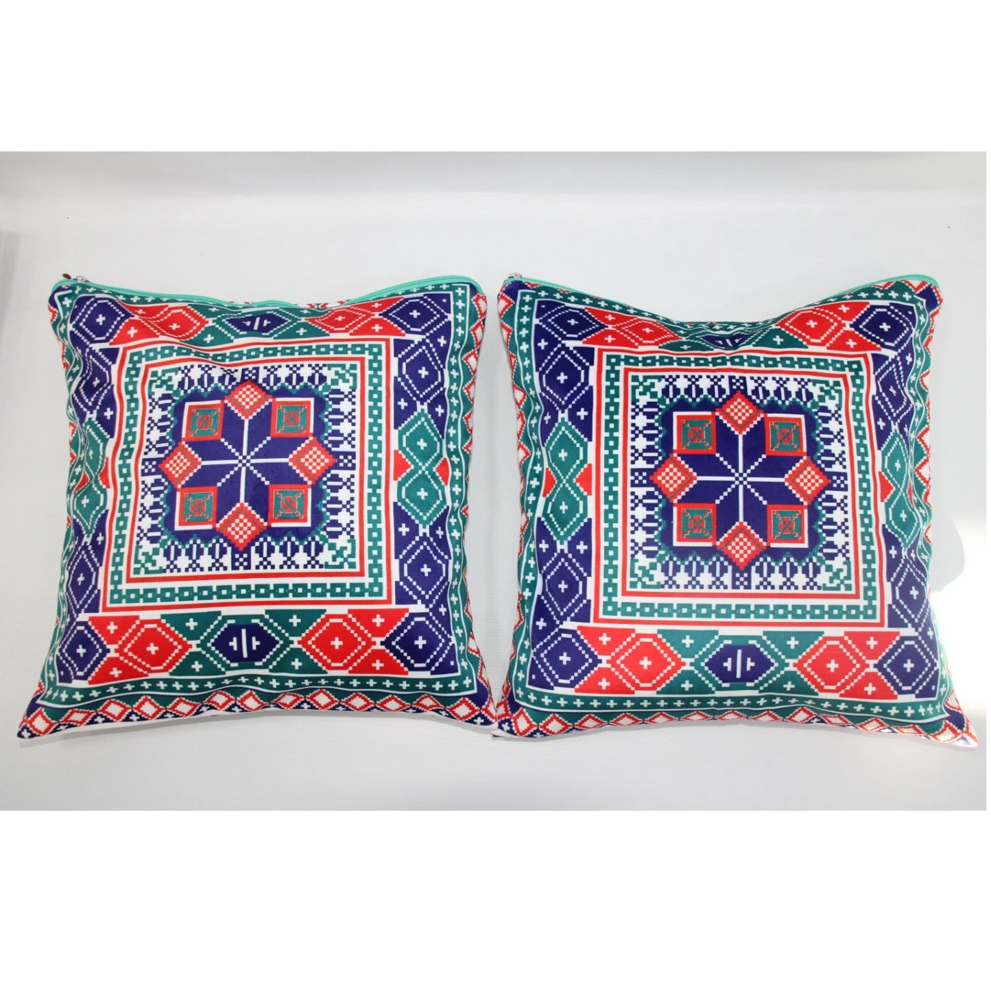 Two square decorative throw pillows with colorful geometric and tribal-inspired patterns in navy blue, red, green, and white, displayed side-by-side against a plain white background.