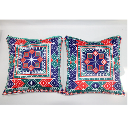Two square decorative throw pillows with colorful geometric and tribal-inspired patterns in navy blue, red, green, and white, displayed side-by-side against a plain white background.
