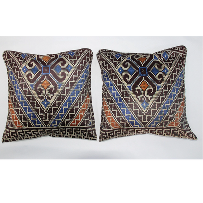 Two square decorative throw pillows with intricate geometric tribal patterns in brown, blue, orange, and cream, displayed side-by-side against a plain white background.