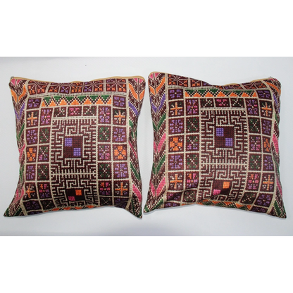 Two square decorative throw pillows with intricate geometric and tribal-style embroidered patterns in brown, purple, orange, green, and beige, displayed side-by-side against a plain white background.